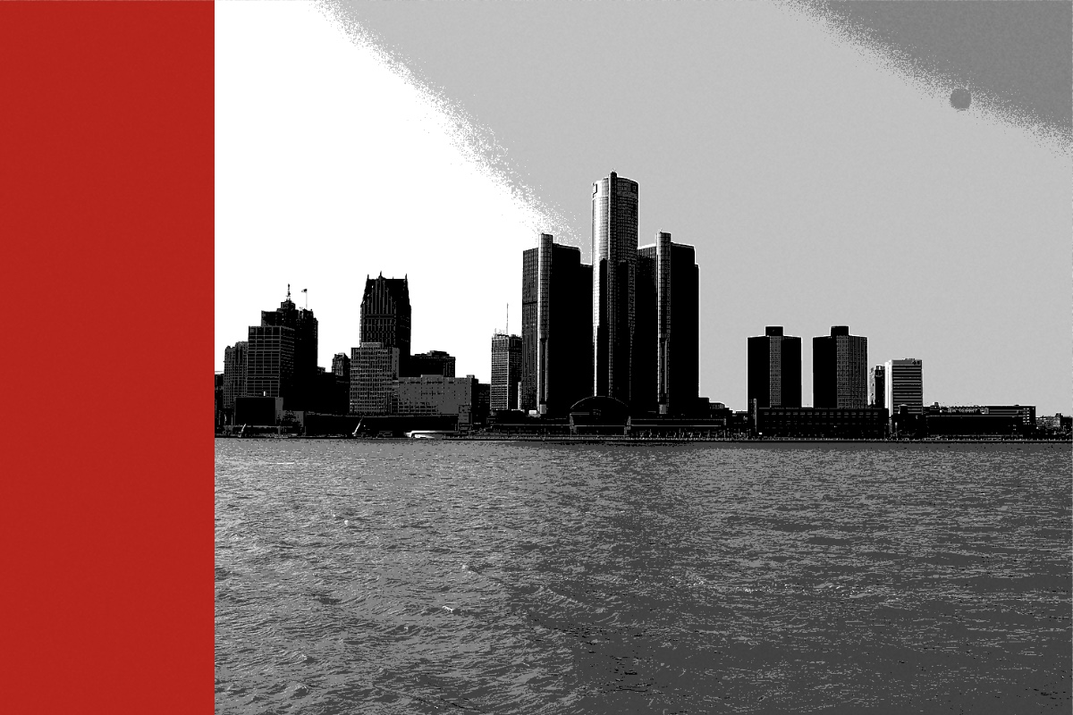 The Detroit skyline seen across the river from the far bank, with the glass towers of the Renaissance Center at the centre and low buildings to either side under a pale sky, in near black and white with a flat red band down the left edge