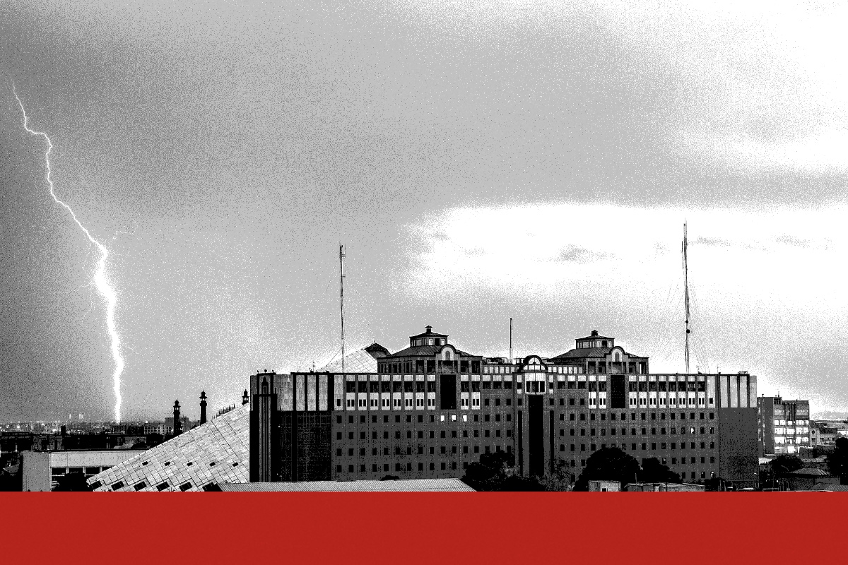 The Islamic Consultative Assembly building in Tehran, a long office block beside the sloping pyramid of its chamber, under storm clouds with a bolt of lightning at the left, in near black and white with a flat red band along the foot of the frame