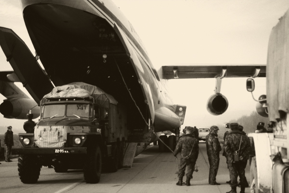 A military truck being offloaded from a transport aircraft, in a warm duotone