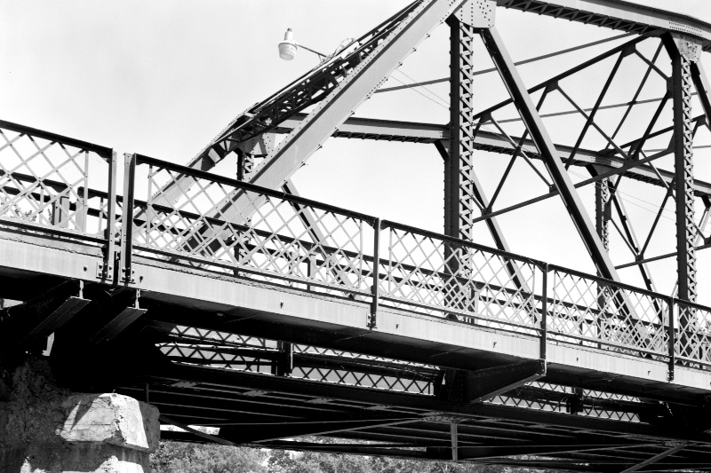The steel truss of a highway bridge seen from the end, in plain black and white