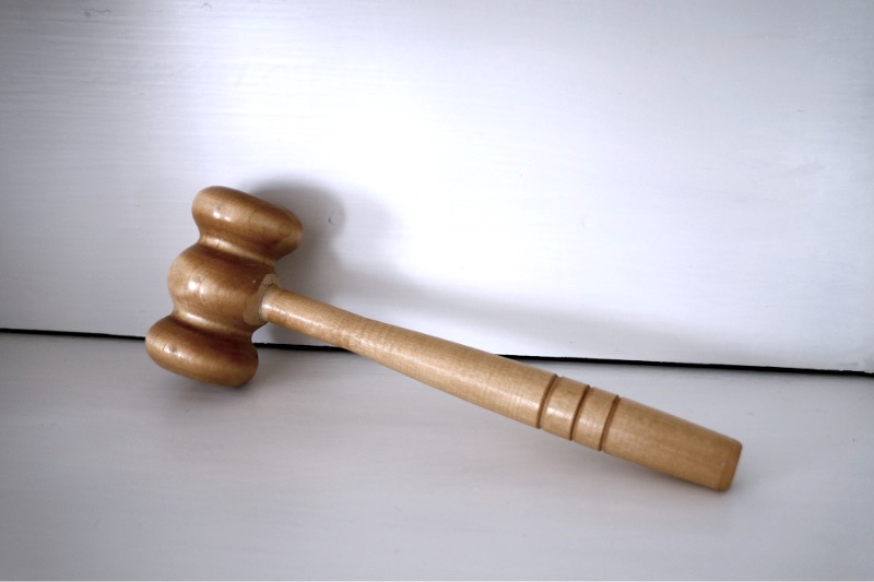 A wooden gavel resting on a plain surface