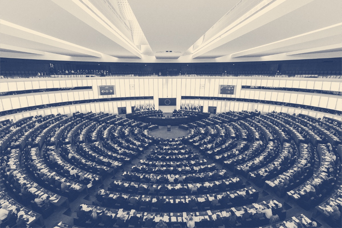 The circular debating chamber of the European Parliament in Strasbourg seen from above, filled with members at their desks, in a slate and bone duotone
