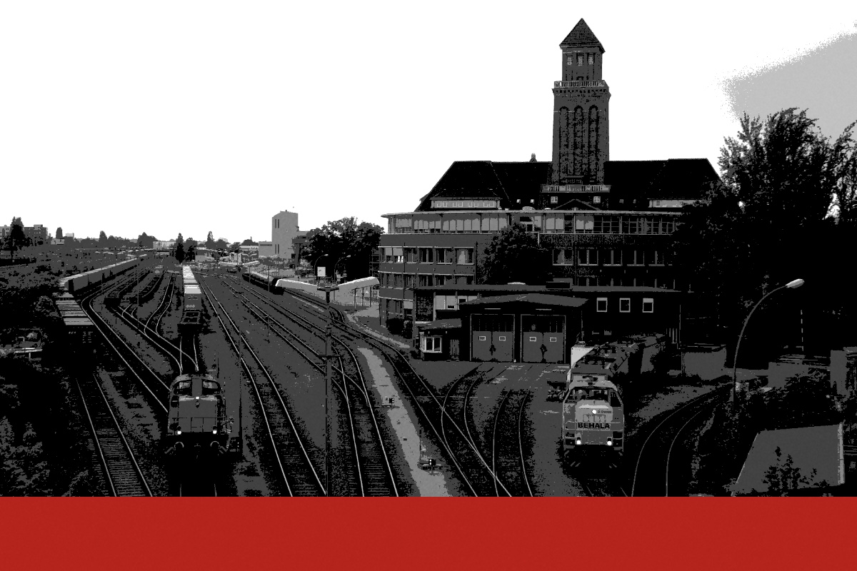 Rail sidings at Berlin’s Westhafen with diesel shunting locomotives on the tracks and a brick administration building with a clock tower behind, in near black and white with a flat red band along the foot of the frame