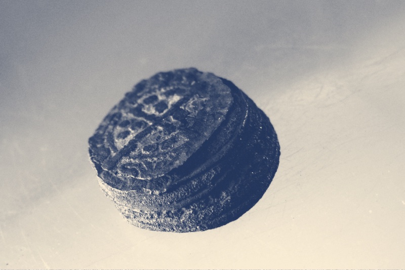 A concreted mass of medieval silver pennies fused together, in a blue duotone