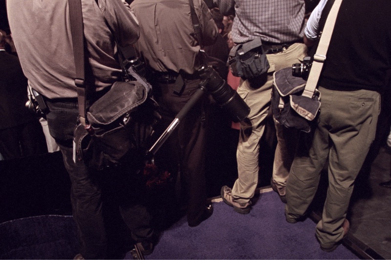Press photographers standing together with cameras raised