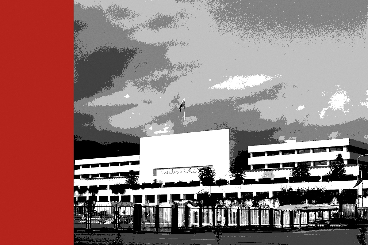 Parliament House in Islamabad, a white modernist block with a flag on the roof behind an iron fence, under heavy clouds, in near black and white with a flat red band down the left edge