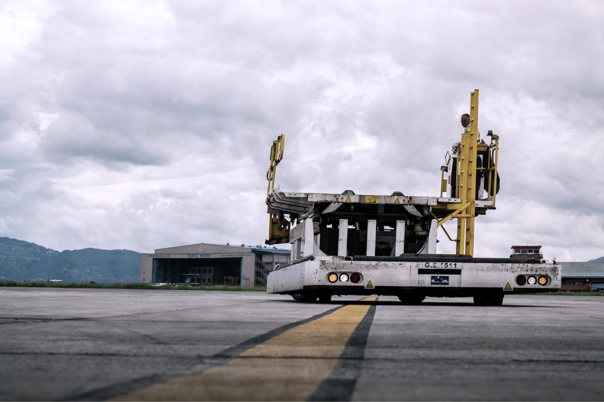 An airport cargo loader on the apron in front of a hangar
