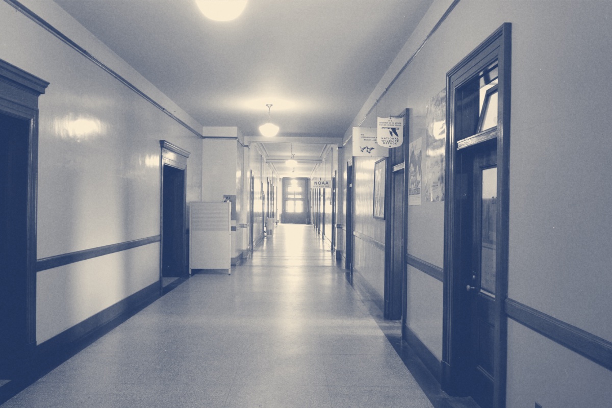 A courthouse corridor with numbered office doors, in a blue duotone