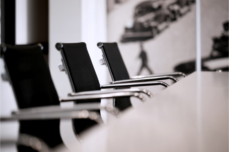 Black office chairs with chrome arms in a row at a conference table