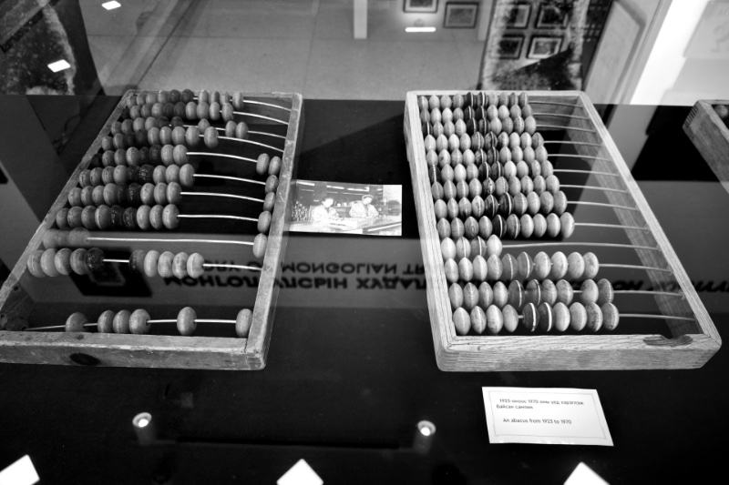 Two abacus frames in a museum case, in plain black and white