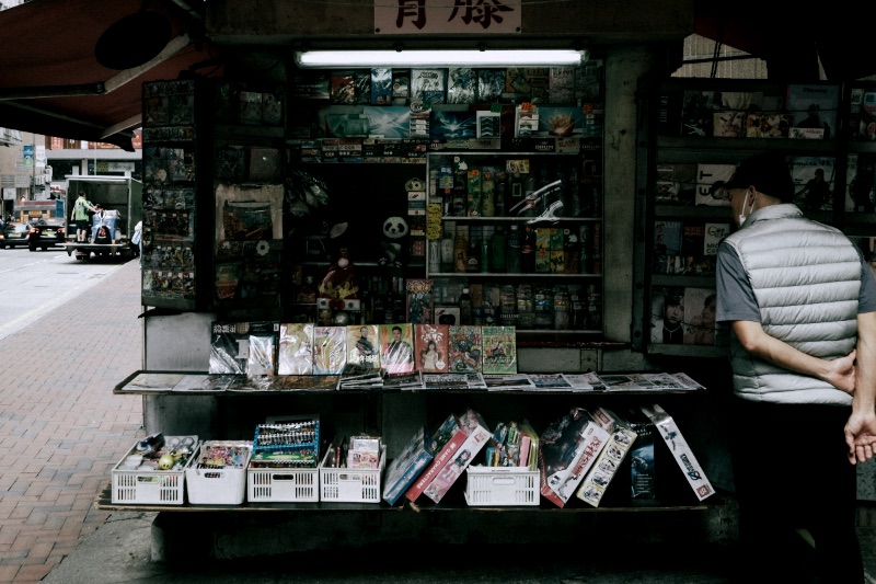 A man observes an outdoor kiosk filled with various products