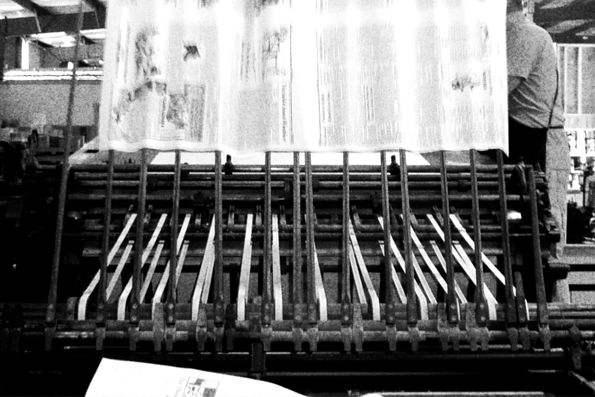 A printing press delivering pages to an output stack, banded in the house treatment