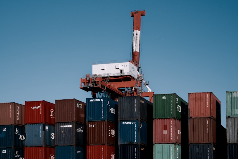 A crane is on top of a large stack of containers