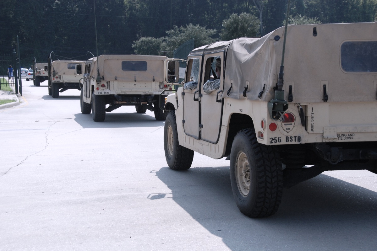 A convoy of military vehicles staged on a paved area