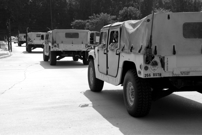 A convoy of military vehicles staged on a paved area