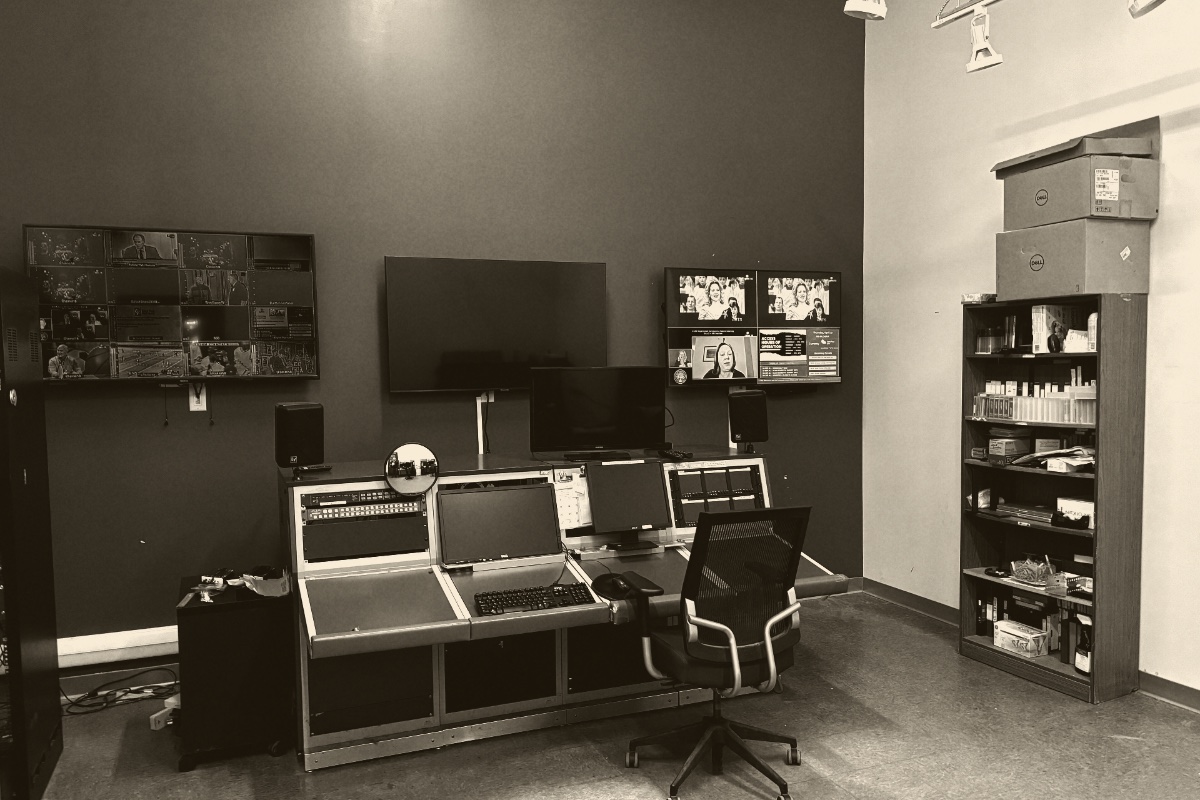 A television master control room, a wall of monitors showing channel feeds above a switching desk