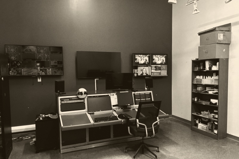 A television master control room, a wall of monitors showing channel feeds above a switching desk