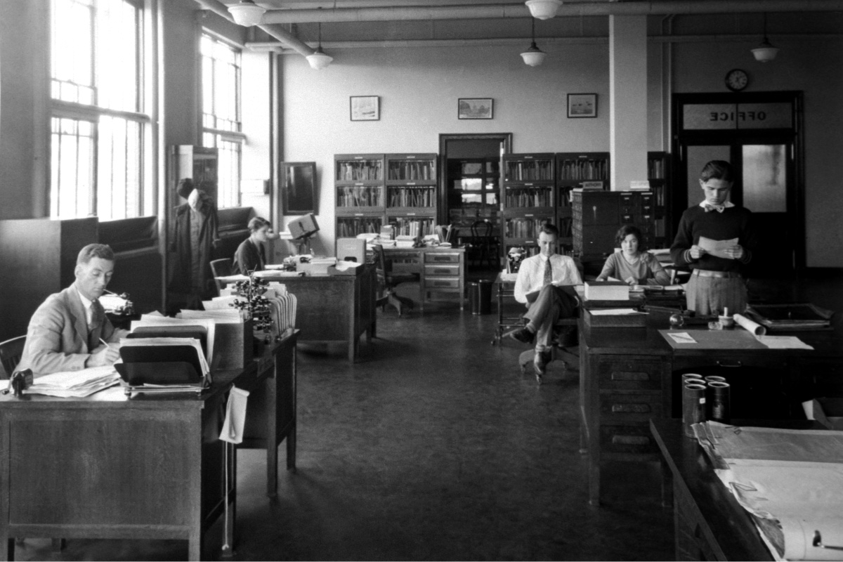 Rows of clerks at desks in an early twentieth century administrative office, in plain black and white