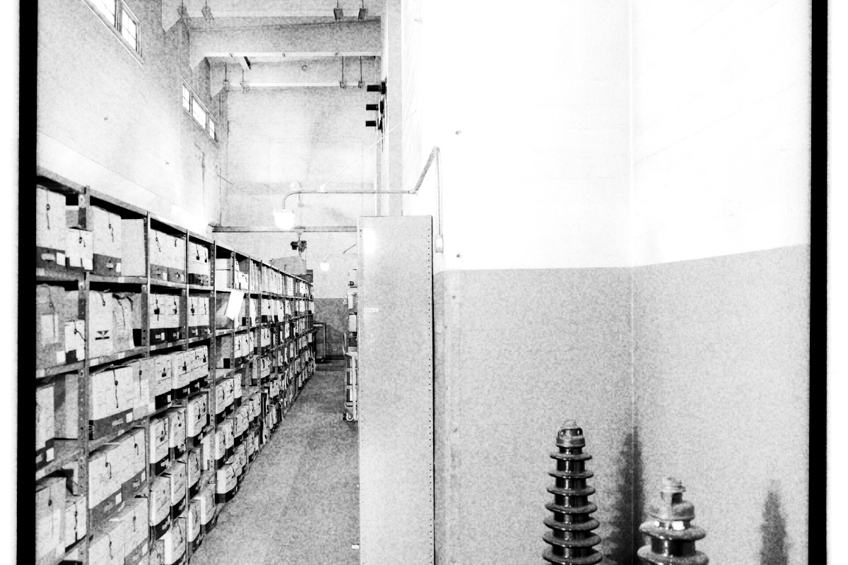 Rows of archival records shelving, in high contrast black and white with coarse grain