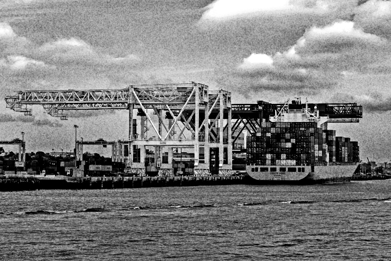 A container ship at a terminal with gantry cranes, in high contrast black and white with coarse grain