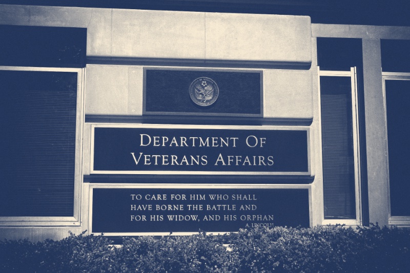 The bronze plaques outside the Department of Veterans Affairs headquarters in Washington, the department seal above its name and Lincoln's words beneath, in a slate and bone duotone