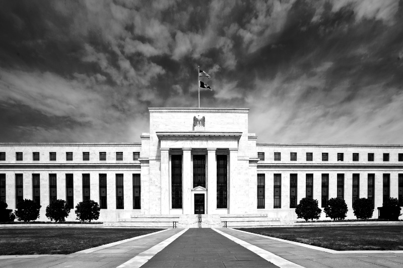 The neoclassical facade of the Marriner S. Eccles Federal Reserve Board Building under a blue sky, in plain colour