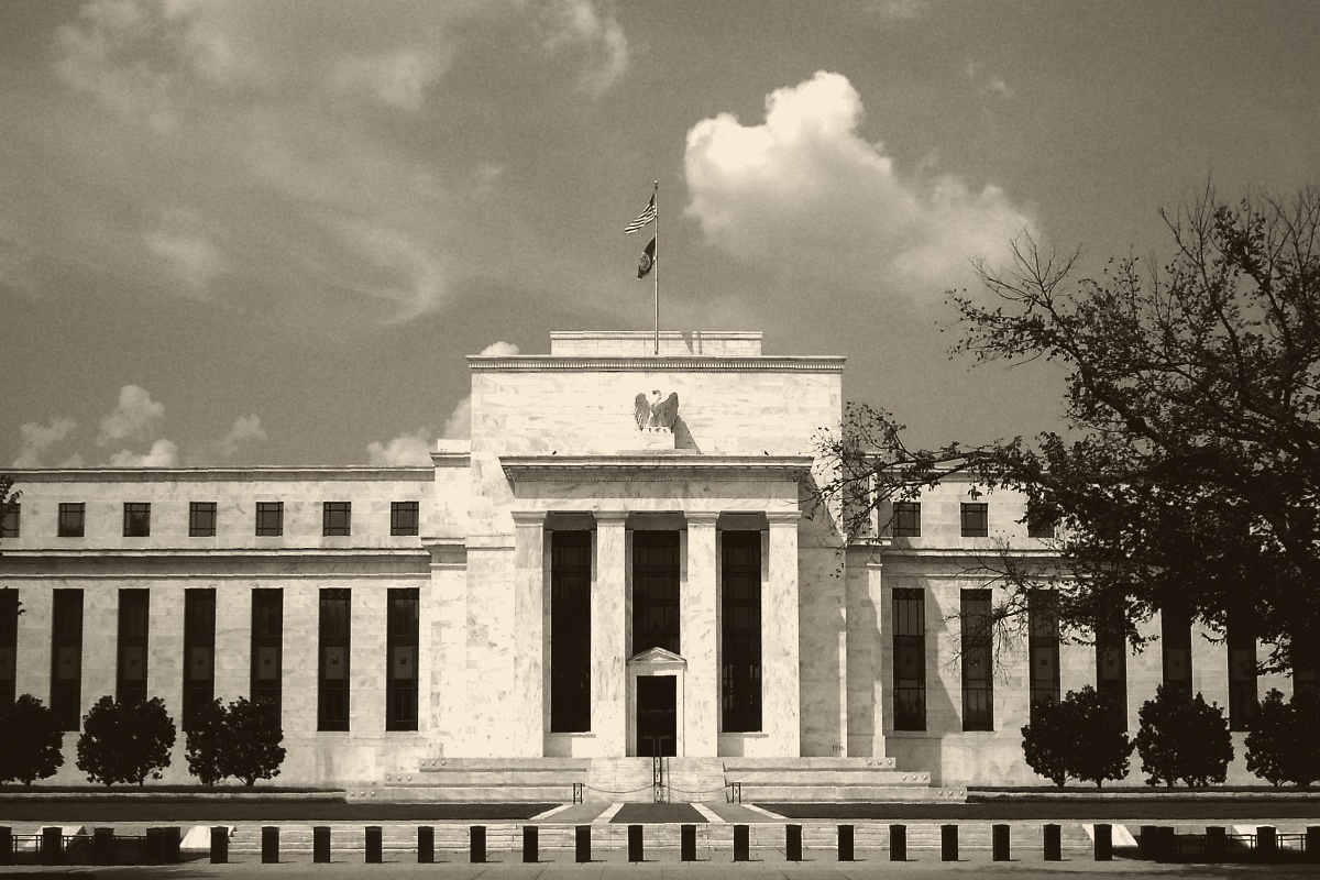 The Marriner S. Eccles Federal Reserve Board Building in Washington, its white marble facade and eagle above the entrance, a flag on the roof, in an ink and bone duotone