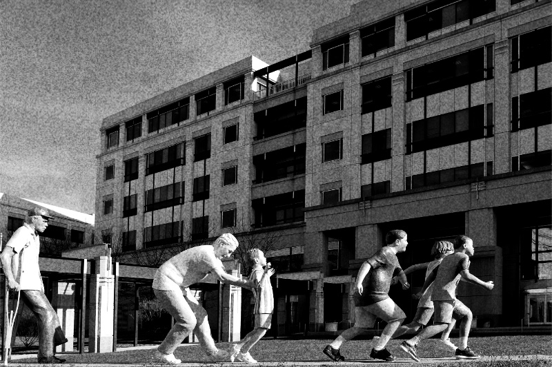 A sculpture of running figures on the lawn outside the Medicare and Medicaid agency's headquarters in Woodlawn, Maryland, in high contrast black and white with coarse grain