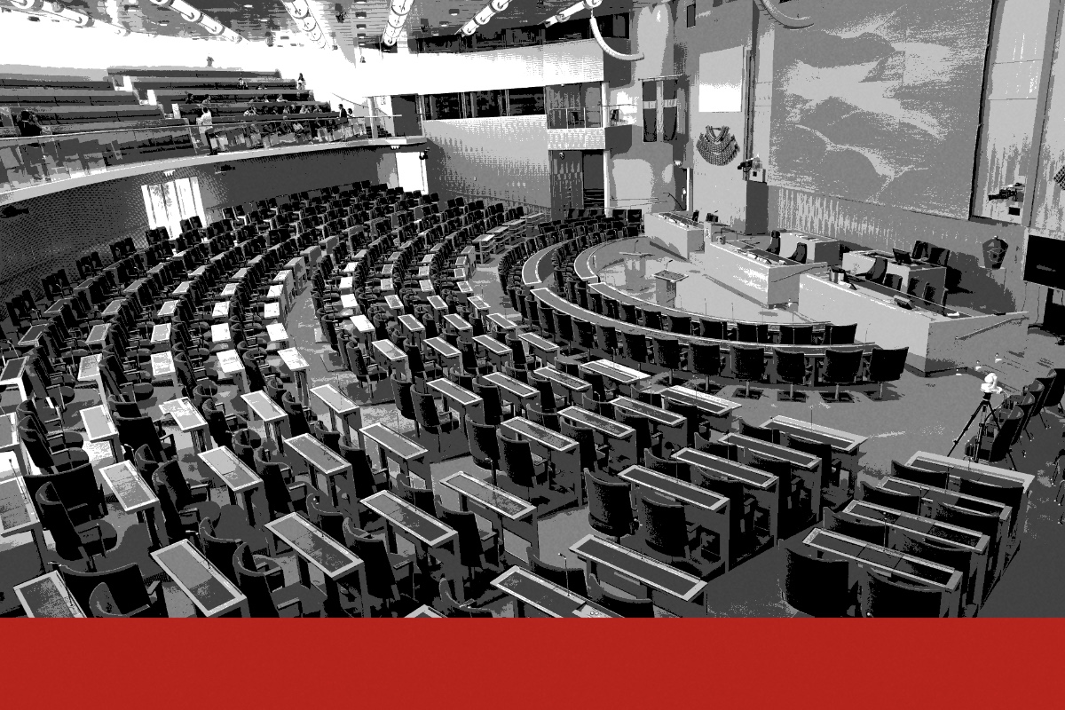 The plenary chamber of the Riksdag in Stockholm seen from a high corner, curved rows of empty desks and chairs facing the Speaker’s rostrum and a large textile hanging, posterised in near black and white with a flat red band along the foot of the frame