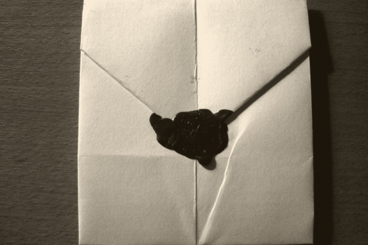 A hand-folded letter closed with a wax seal, in a warm ink and bone duotone