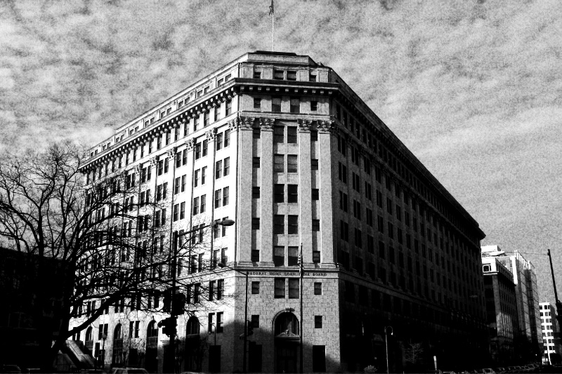 The Classical Revival office building at 320 First Street NW in Washington, its corner entrance and rows of windows rising under a mottled sky, bare trees in front, in grainy high-contrast black and white