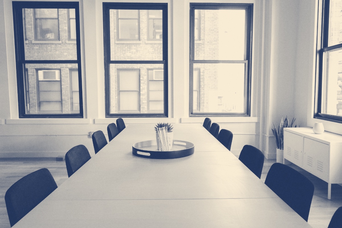 An empty meeting room with a long table and chairs, in a blue duotone
