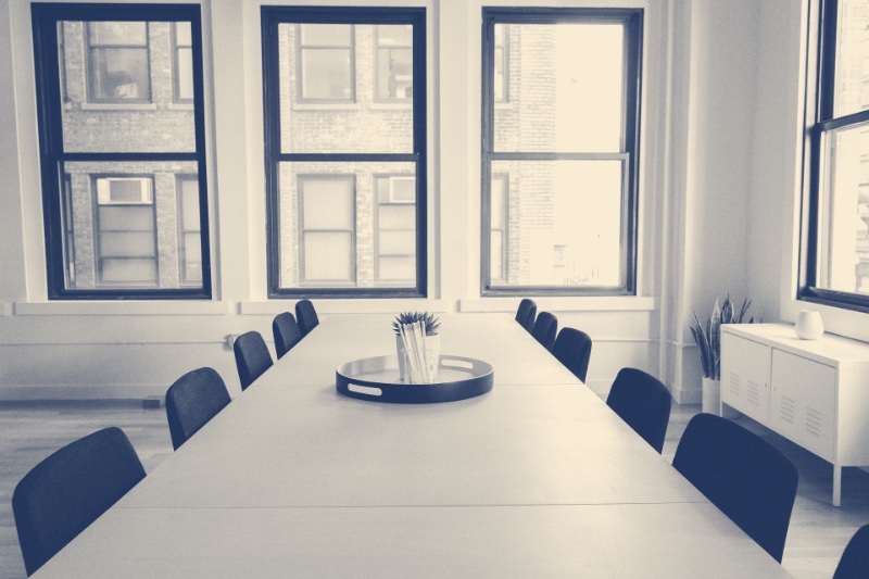 An empty meeting room with a long table and chairs, in a blue duotone