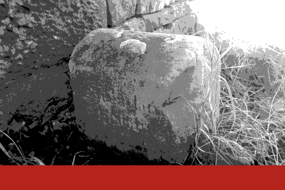 A weathered stone boundary marker in grass, banded in the house treatment