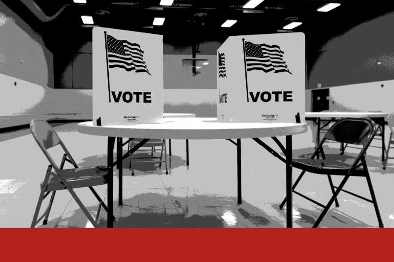 Two voting booths marked with the American flag and the word VOTE on a round table in an empty polling place, folding chairs beside it, in near black and white with a flat red band along the foot of the frame