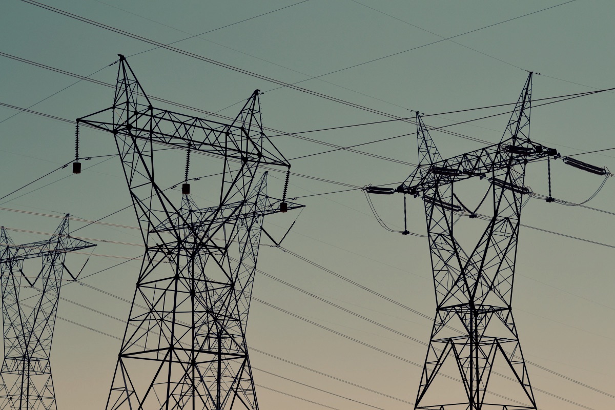 Black transmission towers under green sky