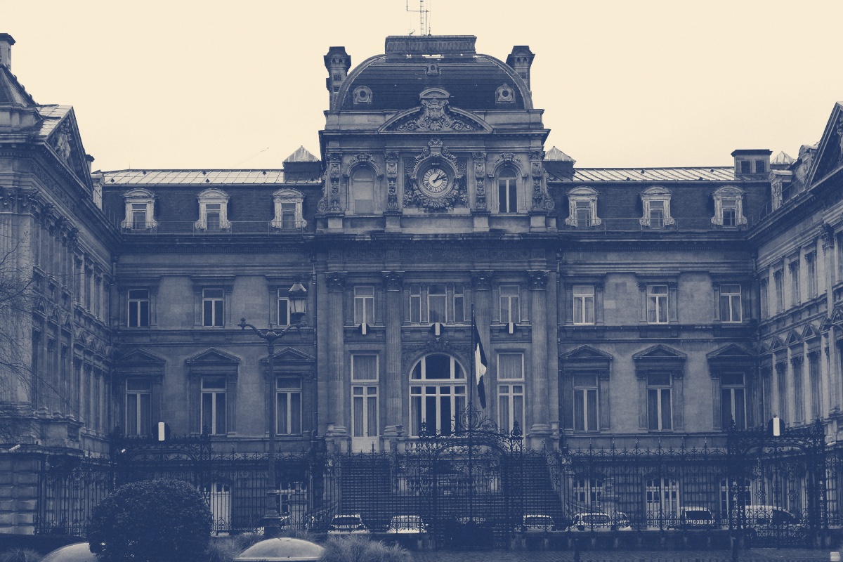 The Hôtel de la Préfecture du Nord in Lille, a symmetrical nineteenth-century stone palace with a domed central pavilion, a clock and tall arched windows behind iron railings, French flags at the entrance, in a slate blue and bone duotone